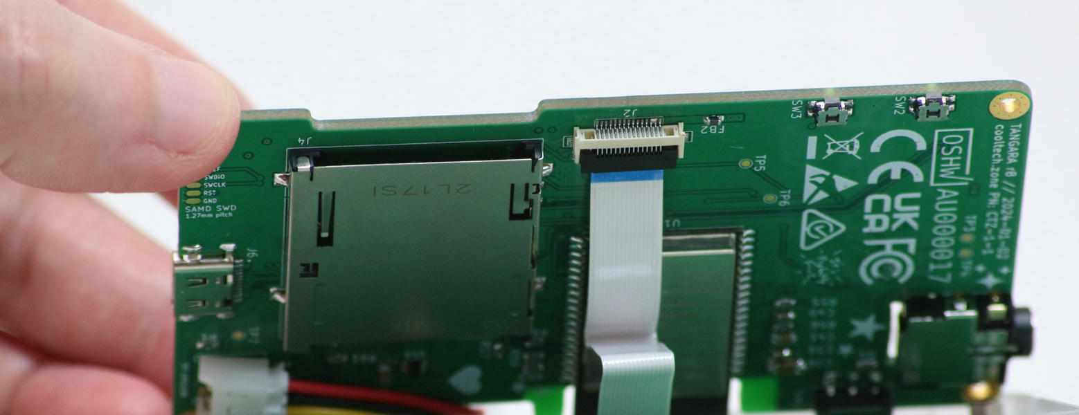 The mainboard is lifted slightly, revealing the ribbon cable and connector